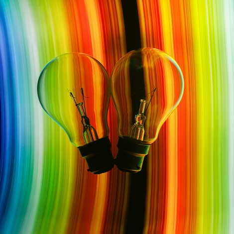 Two lightbulbs with a rainbow background