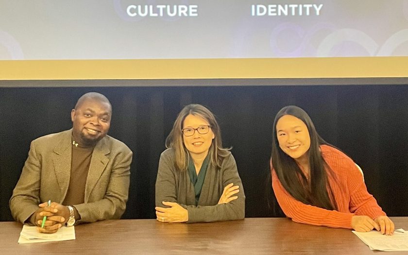 3 IDEC event panelists smiling for a photo in front of a culture & identity backdrop.