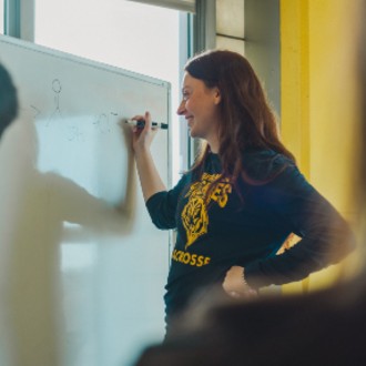 Female student writing chemical structures on a whiteboard