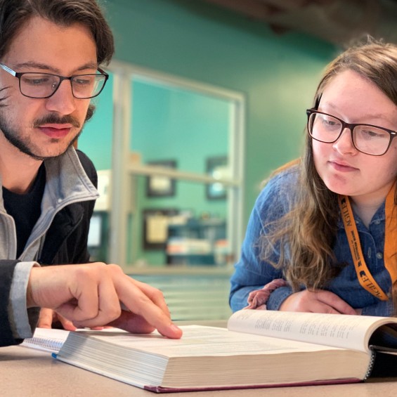 Student and tutor looking at textbook together