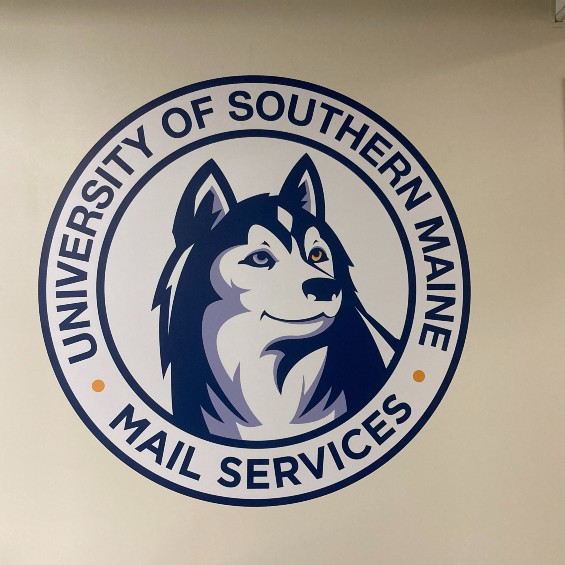Round blue and white logo with the University of Southern Maine written, in blue, at the top in an arch and Mail Services written, in blue, at the bottom. A happy husky in the middle of the logo that has one blue eye and one gold eye.
