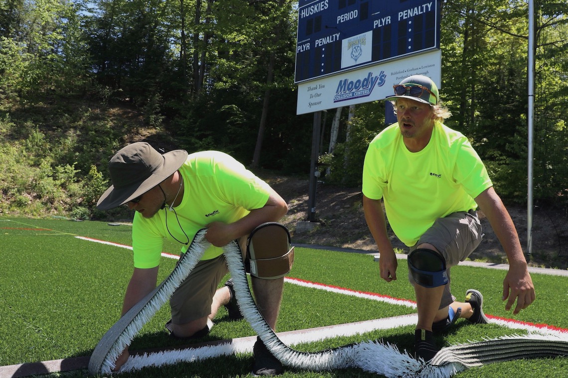 FieldTurf workers secure new surface at Hannaford Field.