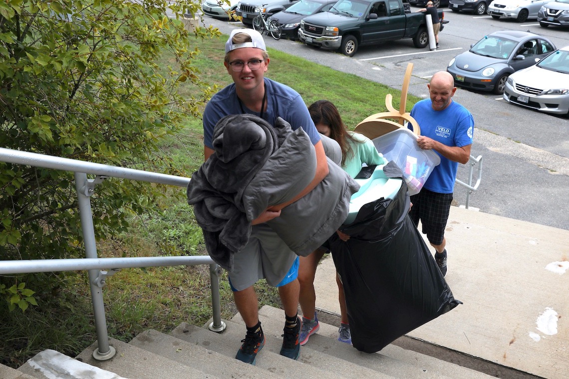Student carries an armful of bedding into Philippi Hall during 2022 Move-In Weekend.