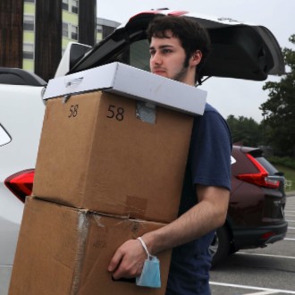 Student hauls two boxes into his new dorm at Philippi Hall during 2022 Move-In Weekend.