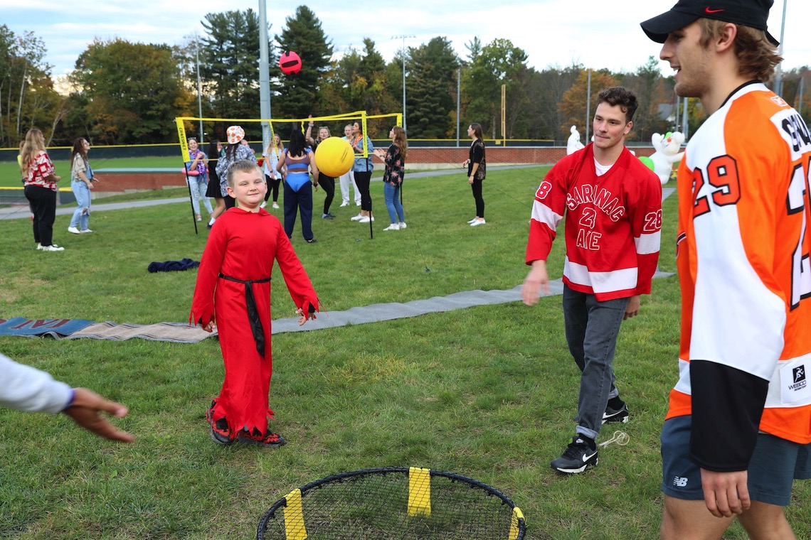 Student athletes show a trick-or-treater a devil of a good time by including him in a round of spikeball at the Husky Community Halloween Party.