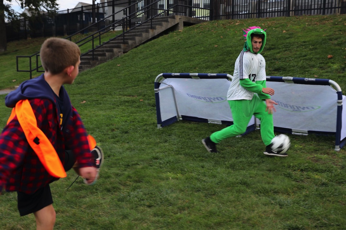 A trick-or-treater tries to score a goal on a member of the Men's Soccer team at the Husky Community Halloween Party.