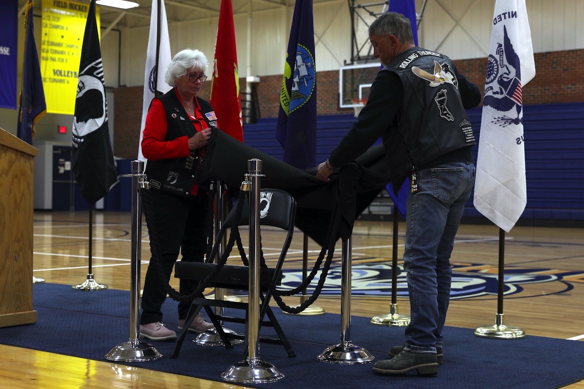 Cindy DeCosta and a fellow member of Rolling Thunder pull back a blanket to reveal the POW/MIA Chair of Honor.