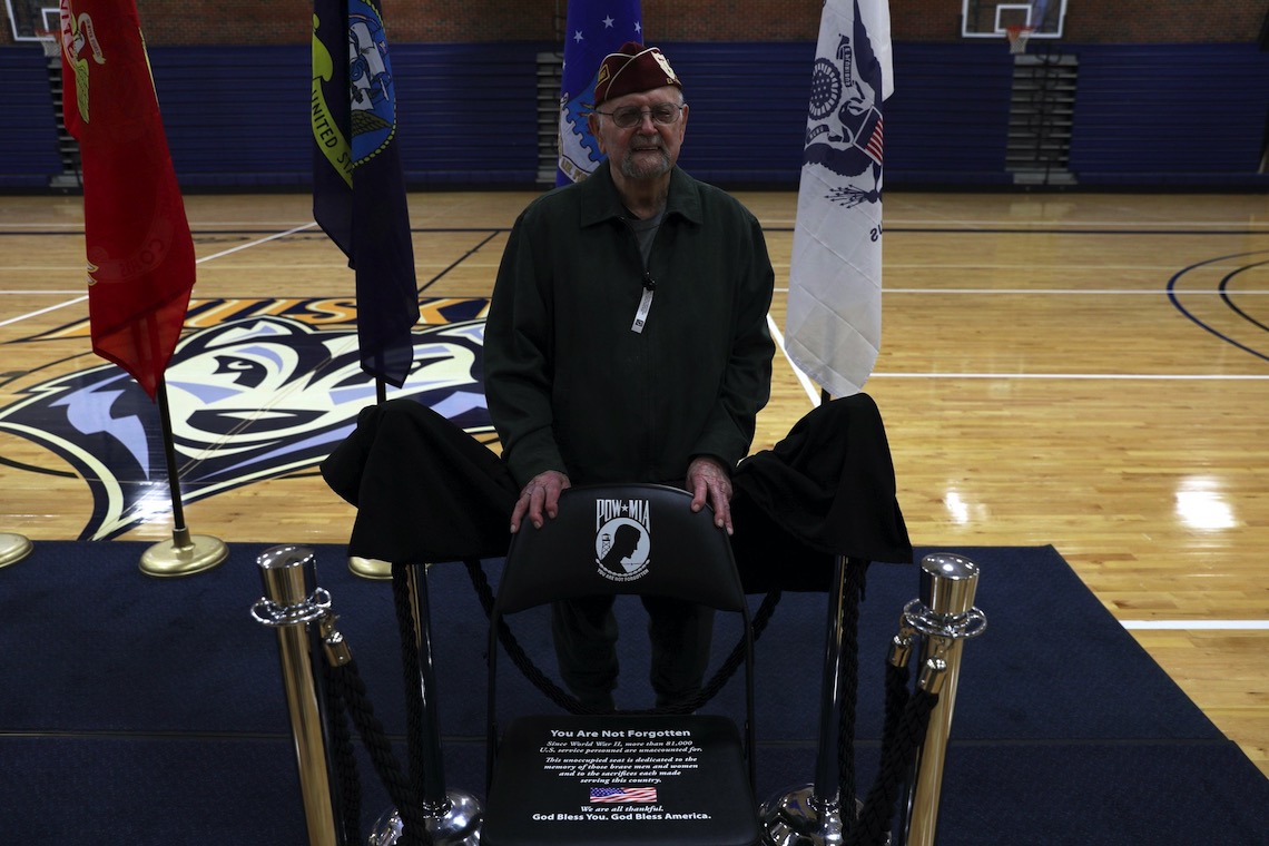 World War II veteran and prisoner of war Leon Tanguay poses beside the POW/MIA Chair of Honor.