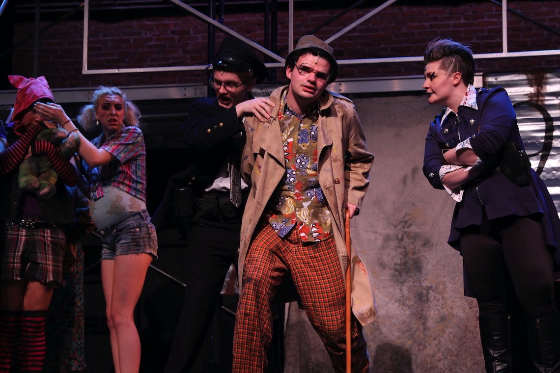 Old Man Strong (Isaac Martel) is punished for breaking sewage restrictions in a scene from Urinetown.