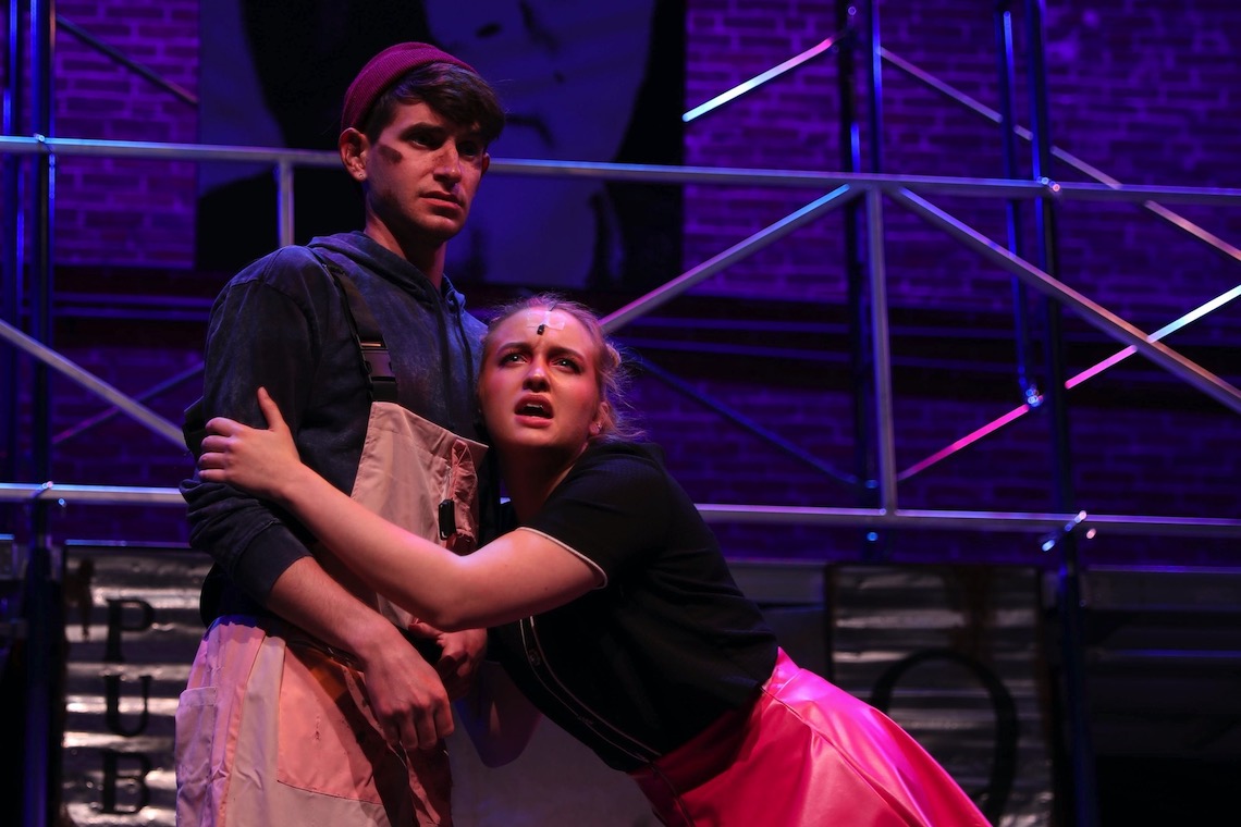 Love blooms between Bobby Strong (Aaron Kircheis) and Hope Cladwell (Emily Bartley) amid the squalor of Urinetown.