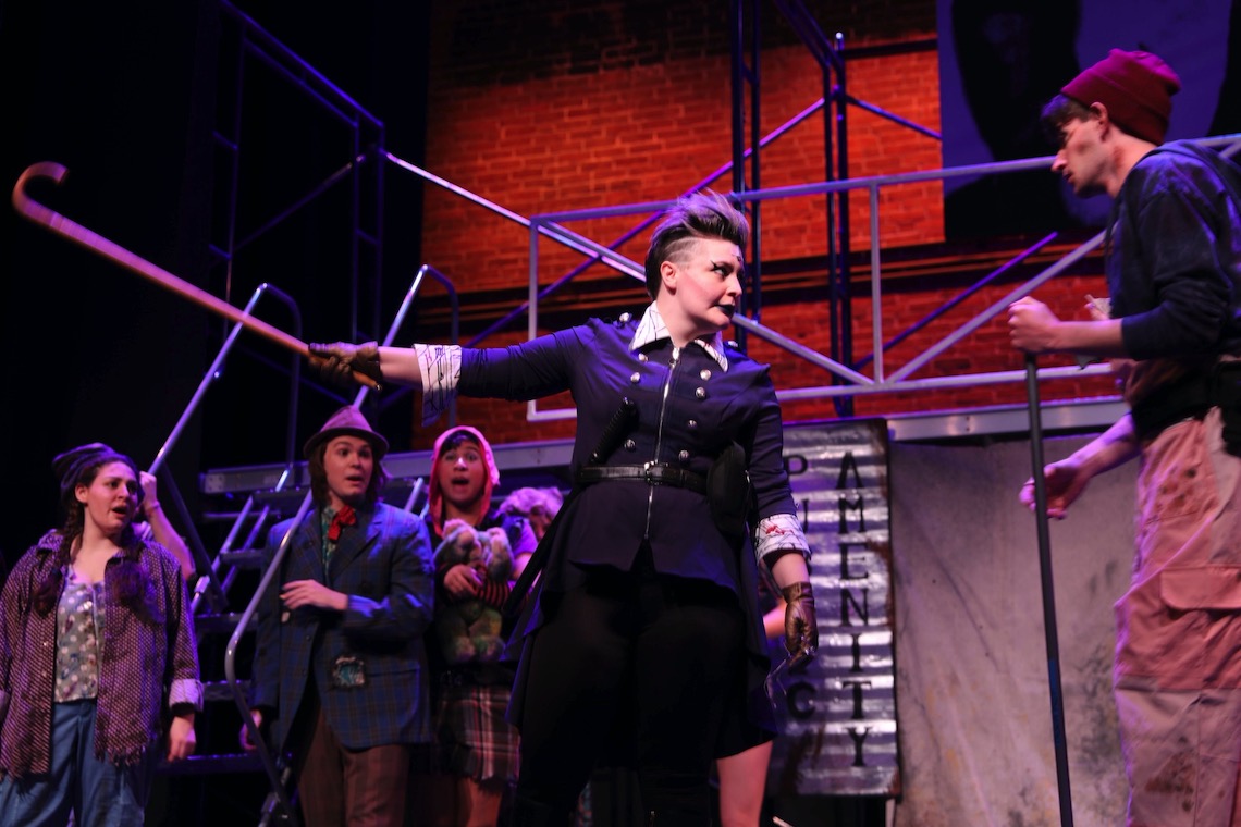 Officer Lockstock (Ciara Neidlinger) enforces the rules of Urinetown with swift brutality.