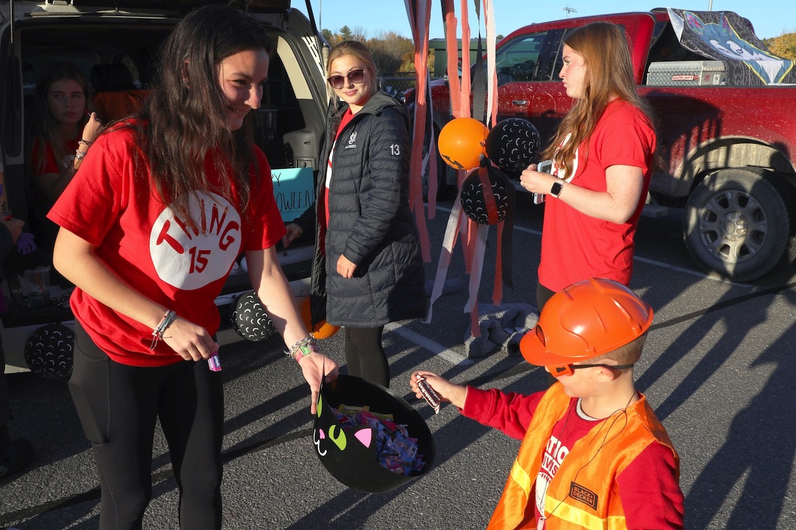 Members of the field hockey team hand out candy at the trunk-or-treat section of the Husky Halloween event.