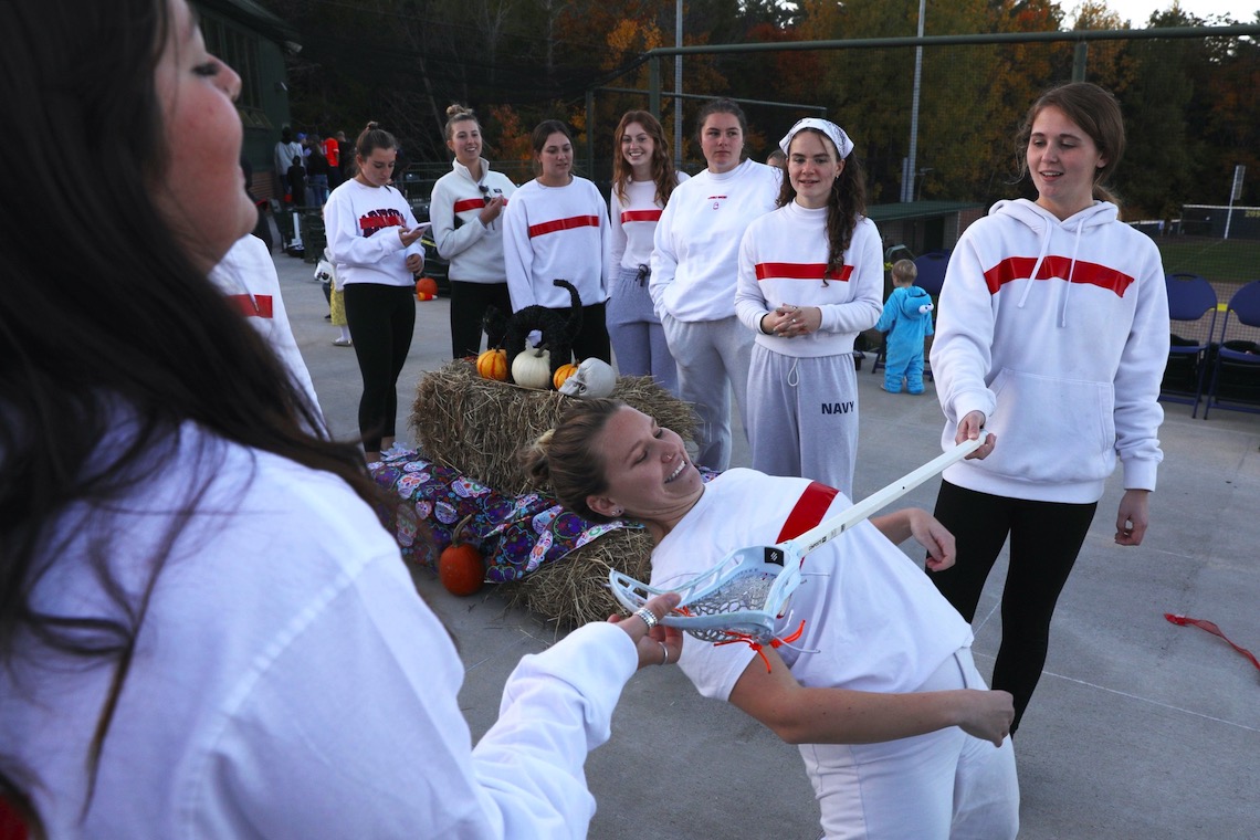 Members of the women's lacrosse team demonstrate to kids at the Husky Halloween event how the limbo is done.