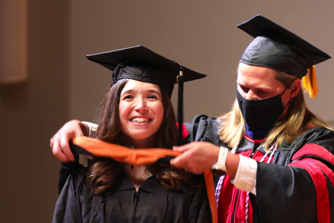 A master's graduate receives the traditional hood signifying completion of her degree at the December 2022 Nursing Convocation ceremony.