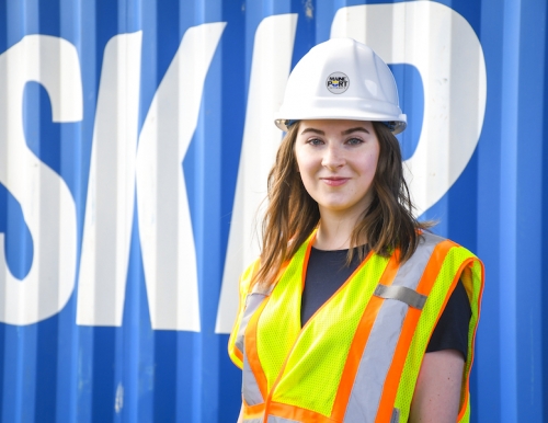 Shaelan Donovan '18 standing in front of an Eimskip shipping container wearing a safety vest and helmet.