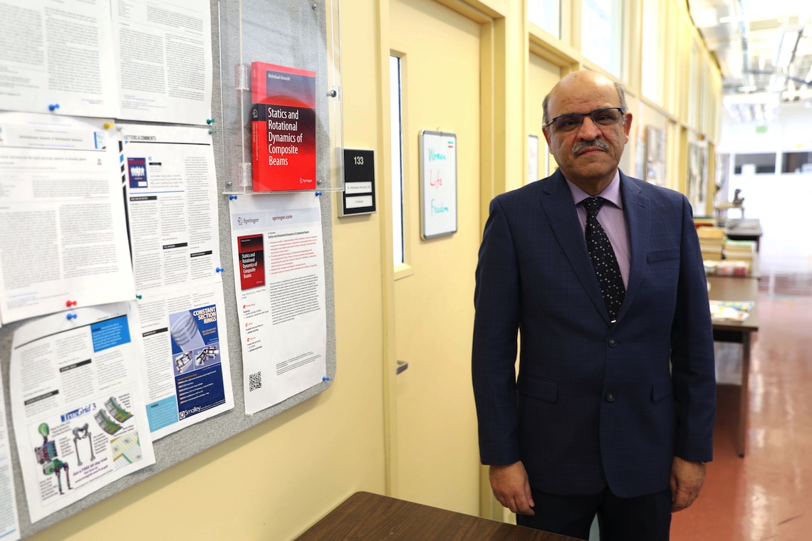 Dr. Mehrdaad Ghorashi stands outside his office door in the John Mitchell Center.