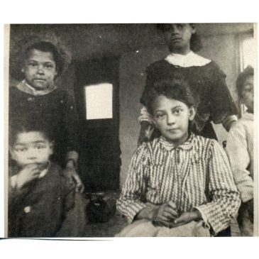Black and white photo of five children in a house on Malaga Island