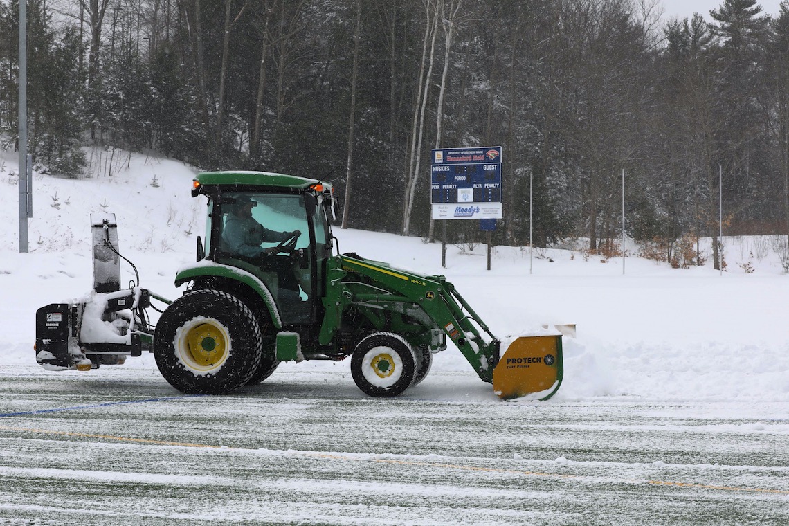 The vehicle used to remove snow from Hannaford Field is a customized John Deere tractor with a plow blade in front and a snowblower on the back.