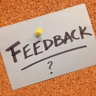 Piece of paper with the word "feedback?" on it tacked to a bulletin board