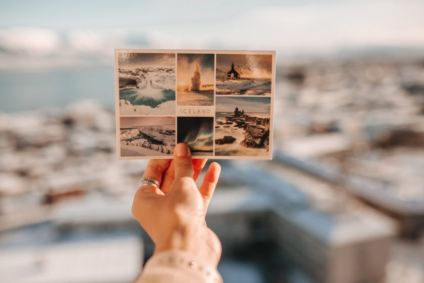 A photo showing a hand holding up a postcard of Iceland