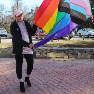 Kip Foster steadies the Intersex-Inclusive Progress Pride Flag as it is raised on the flagpole outside of Corthell Hall.