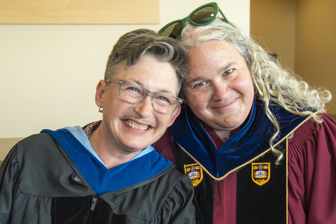 Drs. Caroline Shanti and Libby Bischof pause to smile while donning their regalia ahead of the 2023 Commencement.