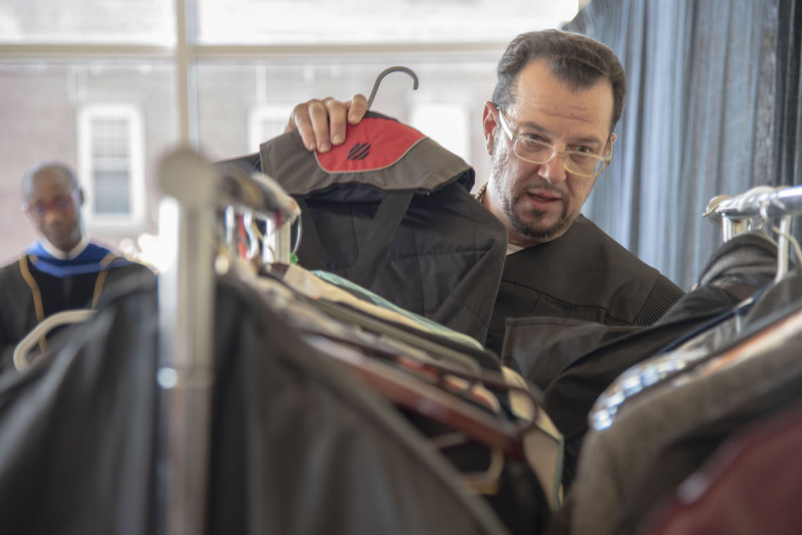 Art Lecturer Damir Porobic stashes away his street clothes after switching into his ceremonial robes ahead of the 2023 Commencement.