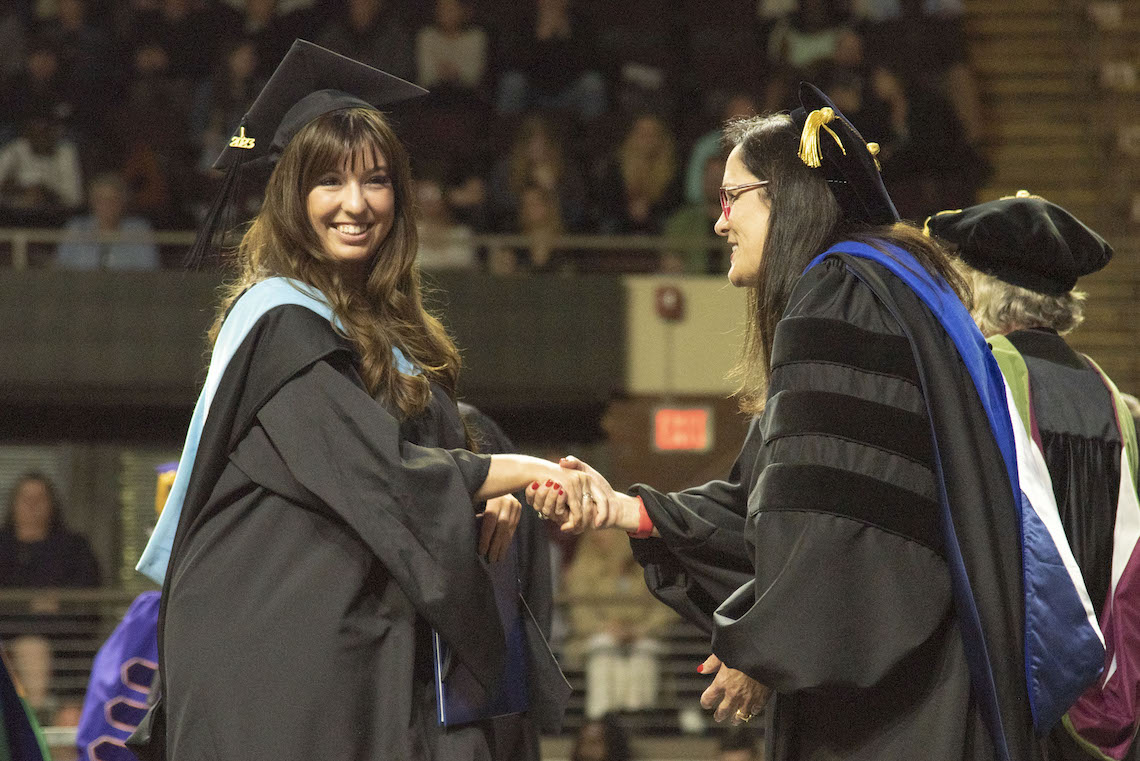 After receiving congratulations from President Jacqueline Edmondson, a student leaves the stage to have her official photograph taken at the 2023 Commencement.