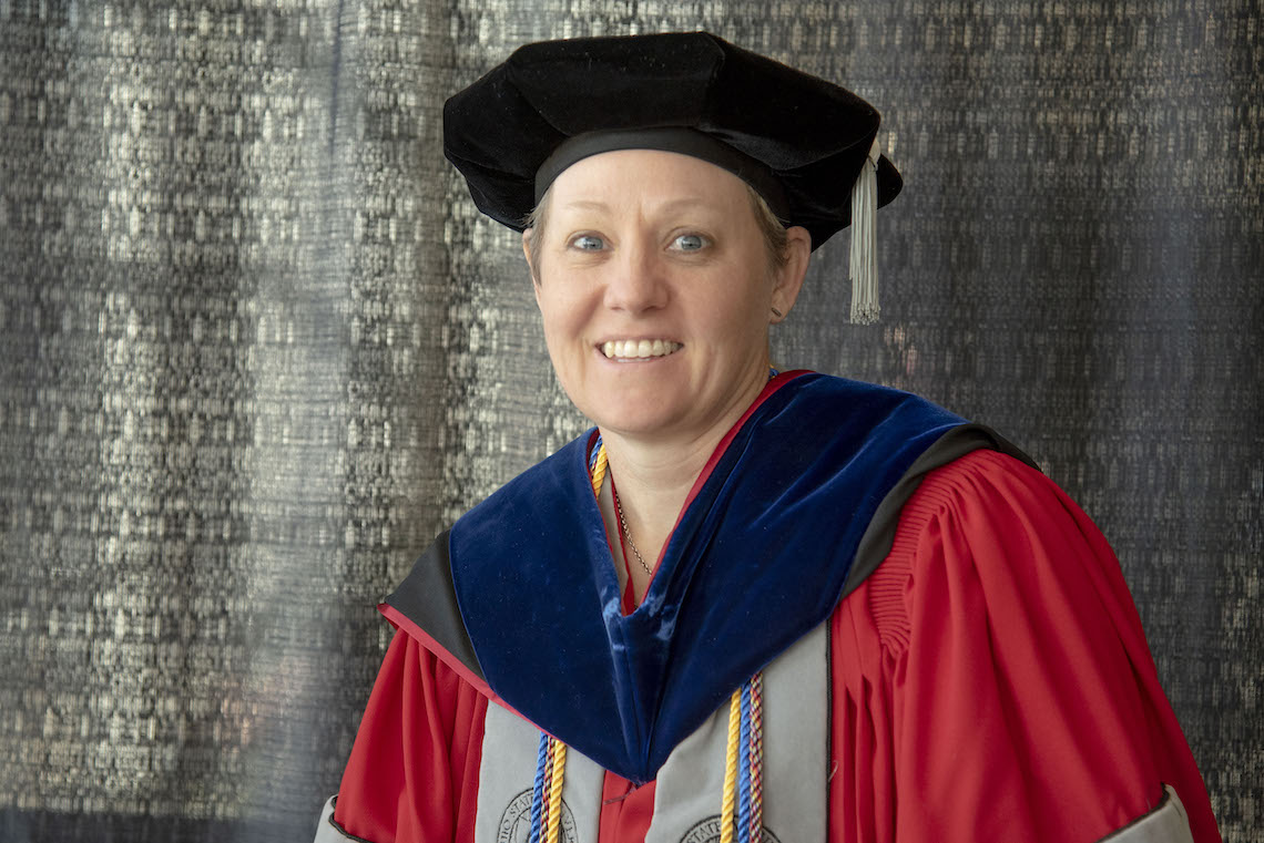 Dr. Heidi Parker is waits for the 2023 Commencement to begin after adjusting the fit of her cap.