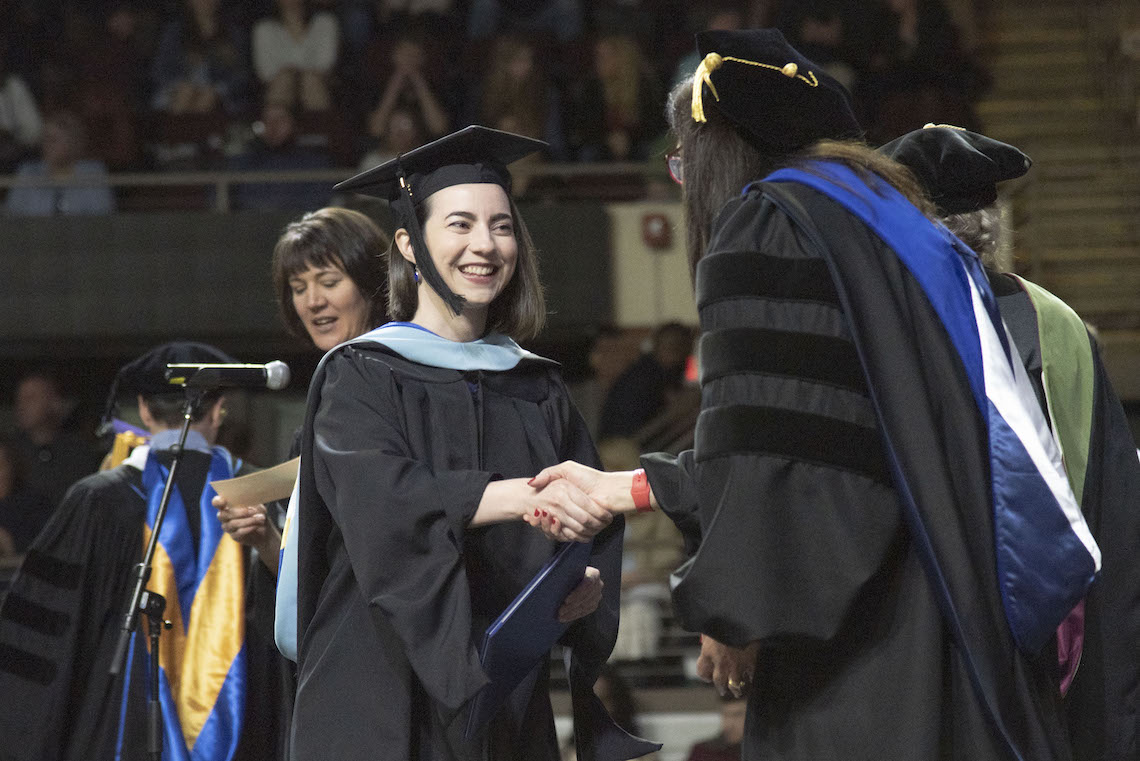 A congratulatory handshake from President Jacqueline Edmondson draws a smile from a new graduate at the 2023 Commencement.