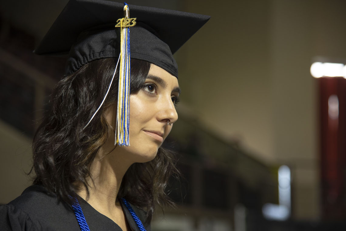 A student strikes a thoughtful pose while waiting in the wings in the minutes before the 2023 Commencement gets underway.