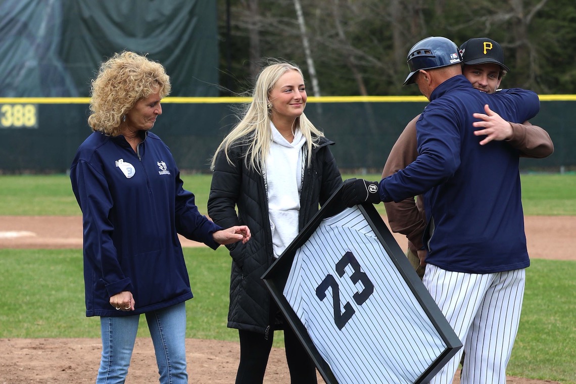 The baseball team presents a framed number 23 jersey as a gift to the family of Vinnie Degifico at the ceremony where his number was retired.