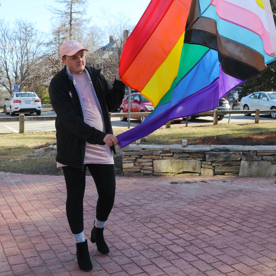 Kip Foster steadies the Intersex-Inclusive Progress Pride Flag as it is raised for the first time on the flagpole in front of Corthell Hall.