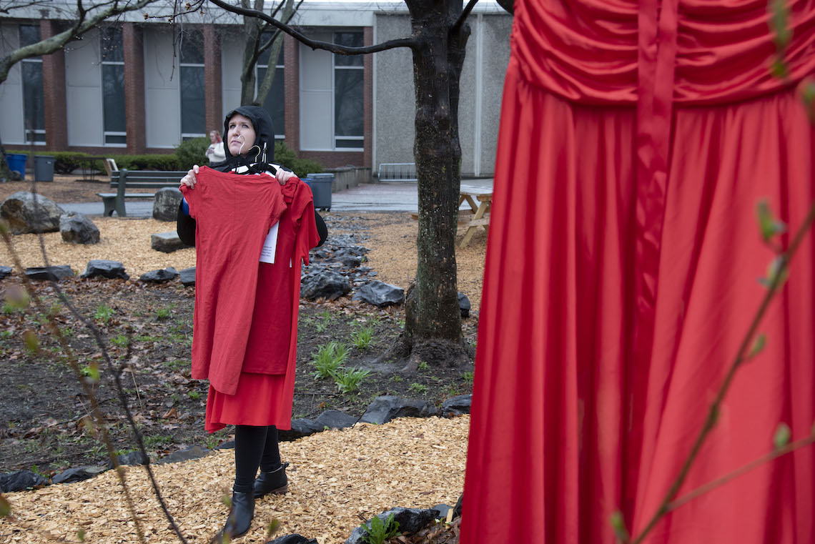Dr. Ashley Towle looks for a sturdy branch from which to hang a dress as part of the REDress Project.