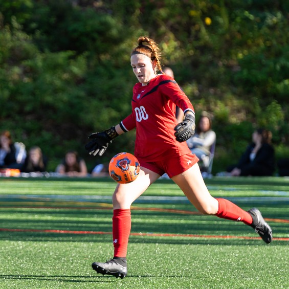 Goalkeeper Breanna Atwood clears the ball downfield during a women's soccer game.
