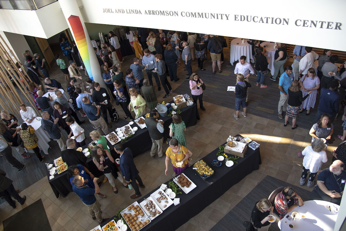 Faculty and staff reconnect at the 2023 Opening Breakfast while enjoying a buffet of fruit and muffins in the lobby of the Abromson Community Education Center.