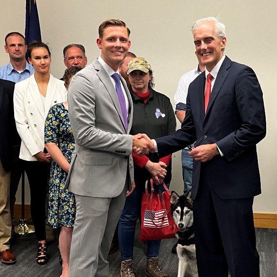 Student and Marine veteran Nate Twombley presents VA Secretary Denis McDonough with a challenge coin during a break in a panel discussion about aid for homeless veterans.