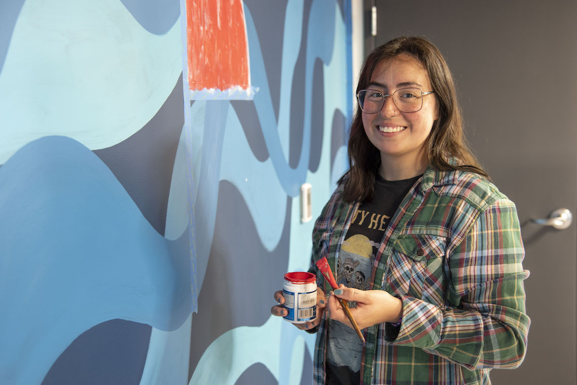 Marissa Joly pauses while painting a medicine wheel as part of her mural at the McGoldrick Center.