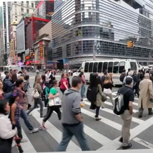 random people cross a busy street in a big city, in front of a modern glass skyscraper