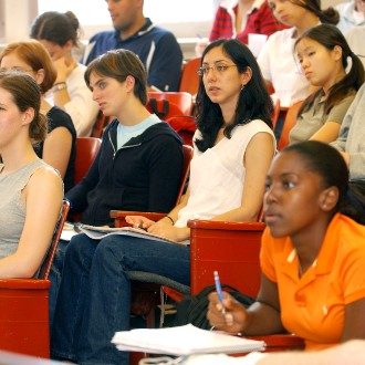 Multiple students sitting in lecture hall watching instructor