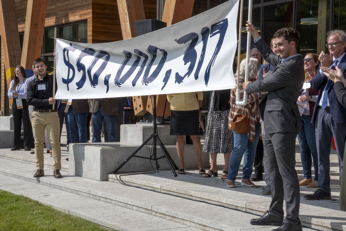A banner is unfurled to reveal the Great University Campaign's fundraising total of $50,010,317 during the ribbon-cutting ceremony for the McGoldrick Center.