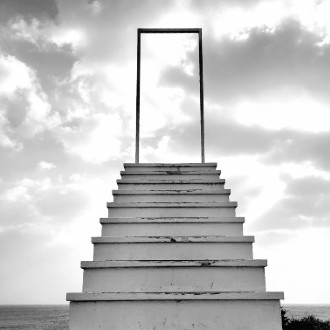 Set of stairs outside, on a beach, leading to an empty doorway