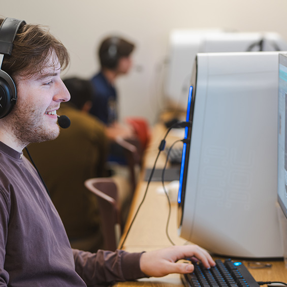 Esports team member Xander Dufour plays "League of Legends" in a university computer lab. Another team member appears in the background.
