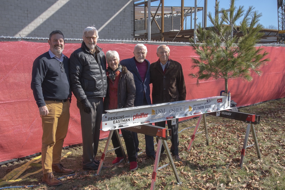 Supporters of the new Crewe Center for the Arts gather around the project's last structural beam before it is hoisted into place.