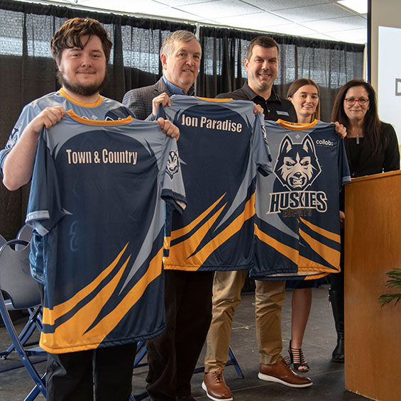 Members of our esports club show off their new team jerseys with university president Jacqueline Edmondson.