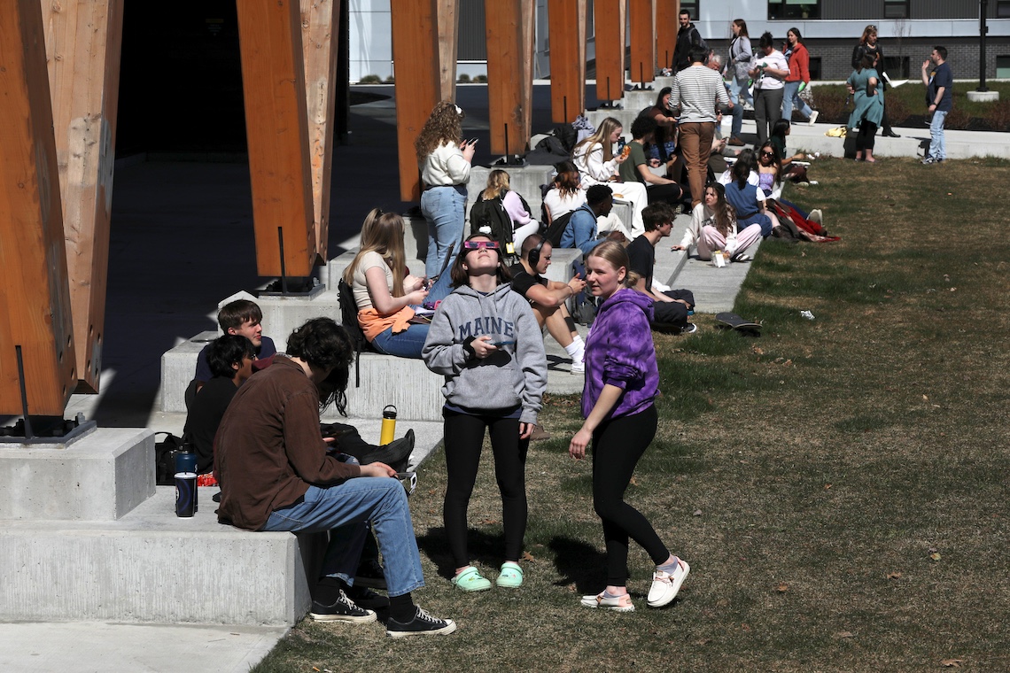 Most students who gathered outside the McGoldrick Center to view the eclipse stayed close to the paved perimeter rather than sit on the grass which was still wet from the recent snow melt.