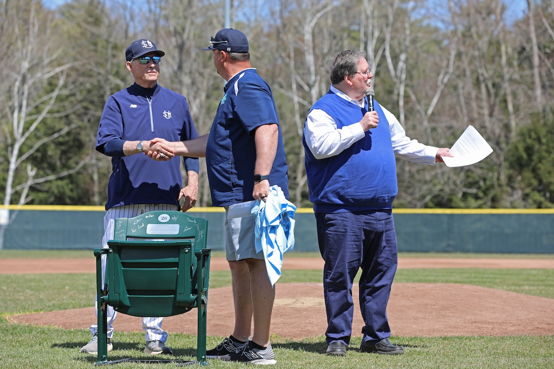 A stadium seat signed by former players is presented to Coach Ed Flaherty as a retirement gift.