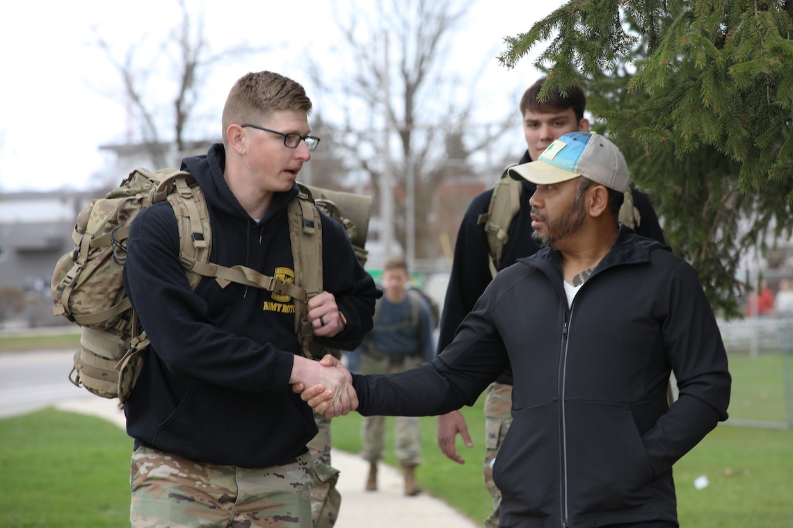Staff Sgt. San Pao (right) shakes hands with ROTC student Beau Vidal as they complete a military-style ruck around Portland's Back Cove in memory of Sgt. Christopher Gelineau.