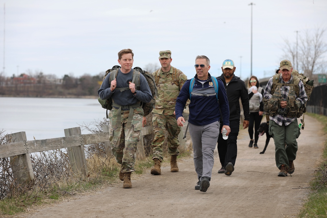 Dean of Students Rodney Mondor (front row, far right) chats with fellow walkers during a military-style ruck around Portland's Back Cove in memory of Sgt. Christopher Gelineau.