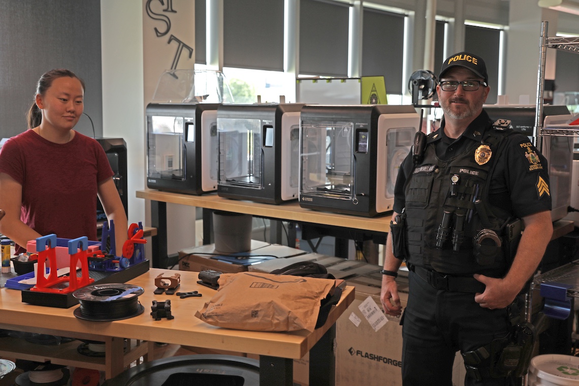 Sgt. Ben Moreland waits while a 3D printer at the MIST Lab makes a locking device that will attach a body-worn camera to his MOLLE vest.